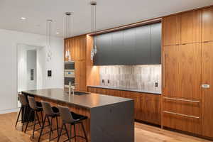 Kitchen with brown cabinets, an island with sink, modern cabinets, and recessed lighting