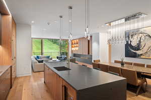 Kitchen featuring modern cabinets, a large island, open floor plan, decorative light fixtures, and brown cabinetry