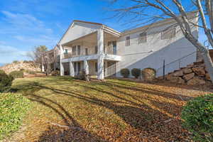 Back of property featuring a lawn, stucco siding, and a balcony