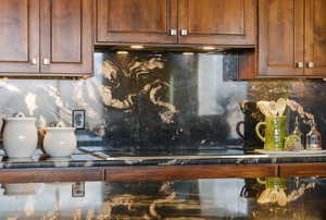 Kitchen view of backsplash, black electric stovetop, and brown cabinetry