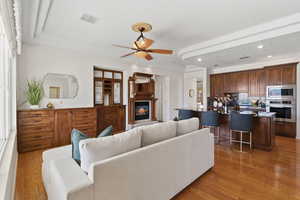 Living area featuring light wood-type flooring, ceiling fan, a glass covered fireplace, and recessed lighting