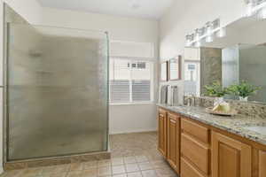 Bathroom featuring double vanity, a stall shower, and light tile patterned floors