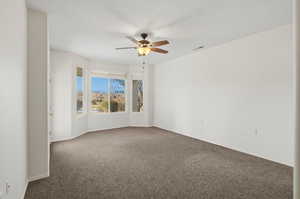 Spare room with carpet flooring, a ceiling fan, and a textured ceiling