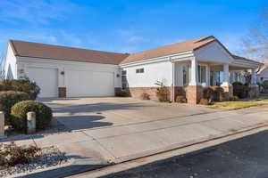 View of front of house with brick siding, concrete driveway, stucco siding, and a tiled roof