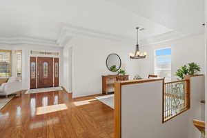Entryway with wood-type flooring, a chandelier, and a raised ceiling