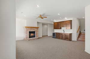 Unfurnished living room featuring light carpet, a brick fireplace, recessed lighting, wet bar, and wine cooler