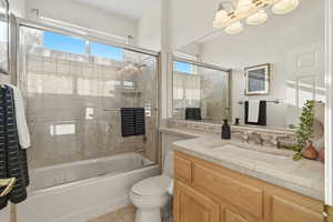 Bathroom with bath / shower combo with glass door, vanity, and plenty of natural light