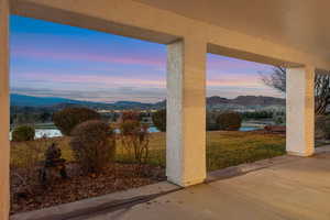 Patio terrace at dusk featuring a mountain view, a patio, and a lawn