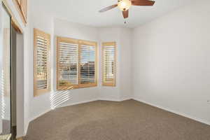 Carpeted empty room featuring a ceiling fan and baseboards
