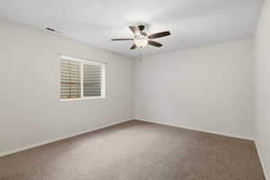 Empty room featuring carpet floors and a ceiling fan
