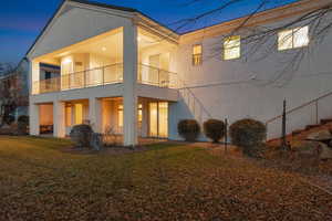 Back of property featuring stucco siding, a lawn, and a balcony