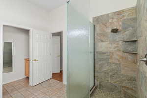 Bathroom with a shower stall and light tile patterned flooring