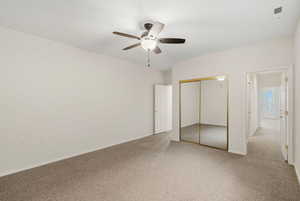 Unfurnished bedroom with a closet, light carpet, and a ceiling fan