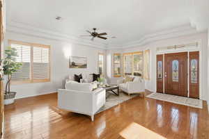Living area with a raised ceiling, light wood-type flooring, and a ceiling fan
