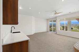 Kitchen featuring light colored carpet, light stone countertops, a mountain view, ceiling fan, and open floor plan