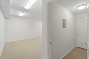 Hall with light colored carpet and electric panel