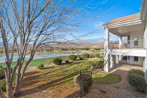View of grassy yard with a water view and a balcony