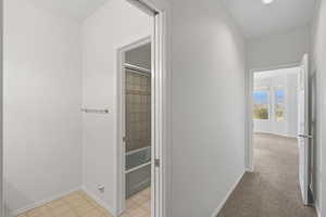 Corridor featuring light colored carpet and light flooring