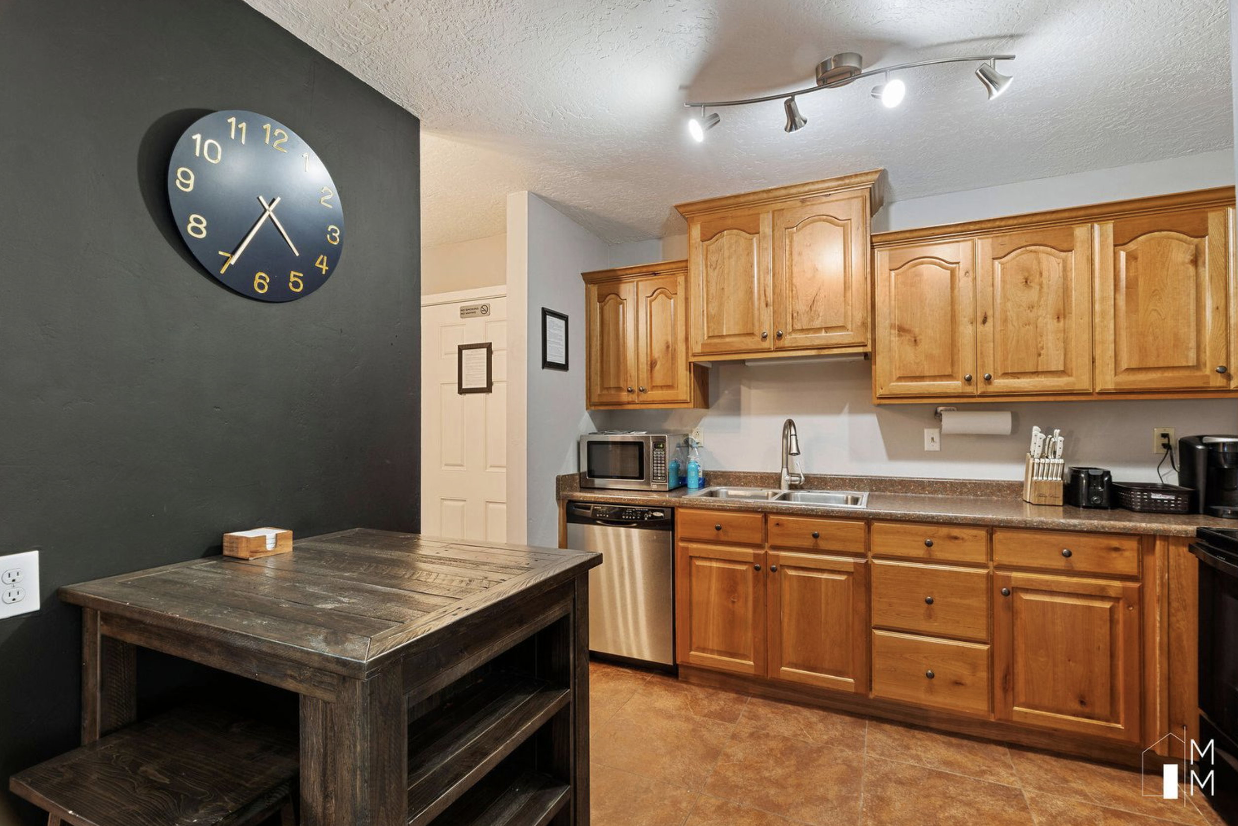 Kitchen featuring stainless steel appliances, a textured ceiling, brown cabinets, and rail lighting