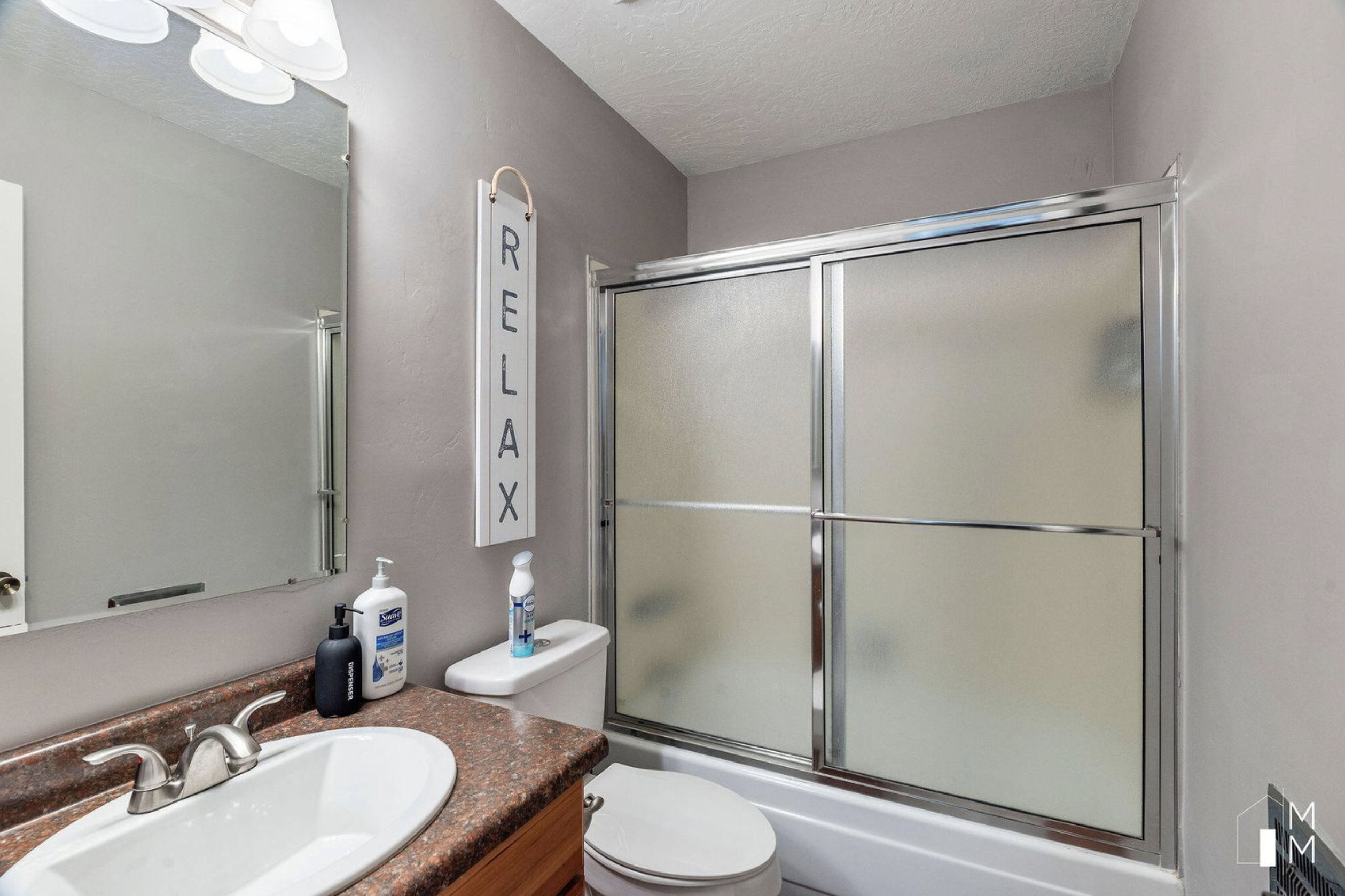 Bathroom featuring vanity, shower / bath combination with glass door, and a textured ceiling