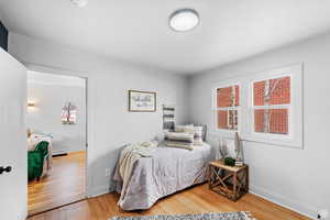 Bedroom with light wood finished floors and multiple windows