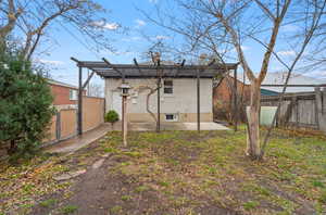 Back of house with brick siding, a fenced backyard, a patio, a gate, and a pergola