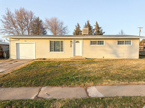 Ranch-style home featuring a front yard, an attached garage, and driveway
