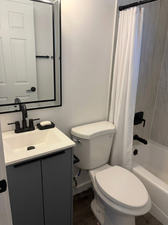 Bathroom featuring shower / tub combo, vanity, and dark wood-style flooring