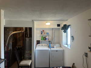Laundry room featuring independent washer and dryer, a textured ceiling, heating unit, and gas water heater