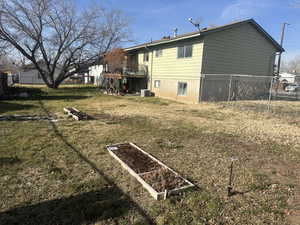 Back of house featuring a vegetable garden, a wooden deck, and stairs