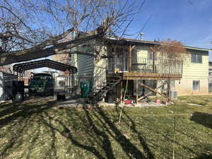Back of house featuring stairs, a lawn, a deck, and a carport