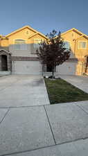 View of front of property with concrete driveway, stucco siding, stone siding, and a garage