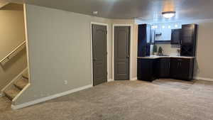 Kitchen featuring light carpet, a textured ceiling, glass insert cabinets, track lighting, and dark cabinets