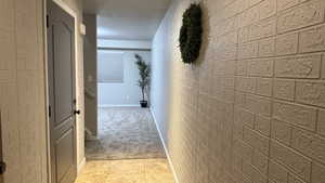 Hallway with light colored carpet and brick wall
