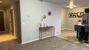 Corridor featuring light tile patterned flooring and light colored carpet