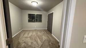Empty room with carpet and a textured ceiling