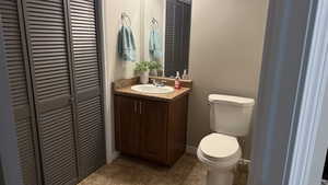 Half bath featuring a closet, vanity, and a textured wall