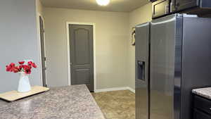 Kitchen with stainless steel refrigerator with ice dispenser and light tile patterned floors