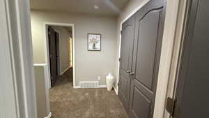 Hallway with dark colored carpet and baseboards