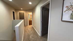 Hall with an upstairs landing, carpet floors, and recessed lighting