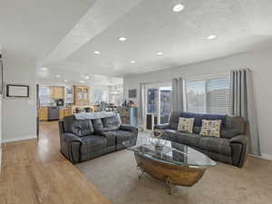 Living room featuring a textured ceiling, healthy amount of natural light, recessed lighting, a chandelier, and light wood-style flooring
