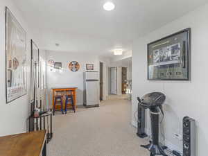 Corridor featuring light colored carpet and a textured ceiling