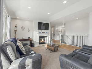 Carpeted living room featuring a glass covered fireplace and recessed lighting