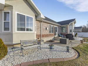 Rear view of property with a patio area, brick siding, stucco siding, and a shingled roof