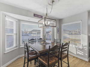 Dining space with light wood-type flooring, a chandelier, and a textured ceiling
