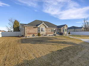 Back of property featuring a fenced backyard, brick siding, a patio area, and roof with shingles