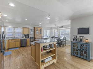 Kitchen featuring dark stone countertops, open shelves, healthy amount of natural light, decorative light fixtures, and a textured ceiling
