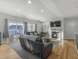 Living area with a textured ceiling, a glass covered fireplace, light wood-style floors, and recessed lighting