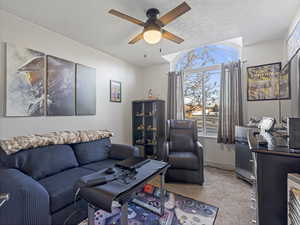 Living area featuring carpet, a textured ceiling, ceiling fan, and an office area