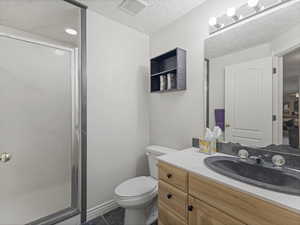 Full bath with a stall shower, vanity, and a textured ceiling